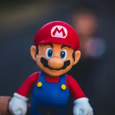 Figurka Mario, jak z gier na telefon za darmo. Czerwona czapka z literą M, niebieskie ogrodniczki i białe rękawiczki.