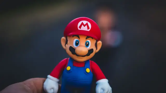 Figurka Mario, jak z gier na telefon za darmo. Czerwona czapka z literą M, niebieskie ogrodniczki i białe rękawiczki.